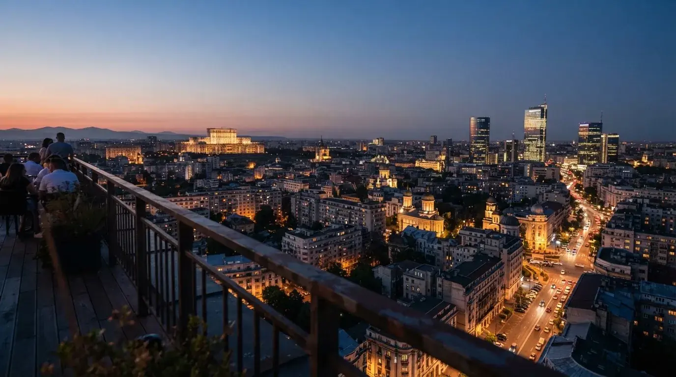 Vedere panoramică de seară asupra unui oraș românesc cu luminile aprinse, privită de pe o terasă înaltă.